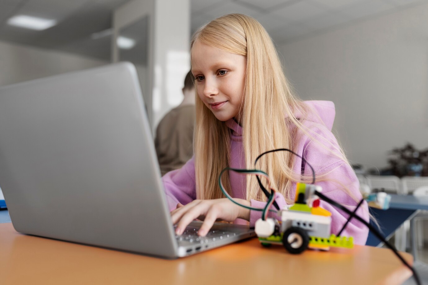 Student programming a robotic rover with electronic parts and a laptop